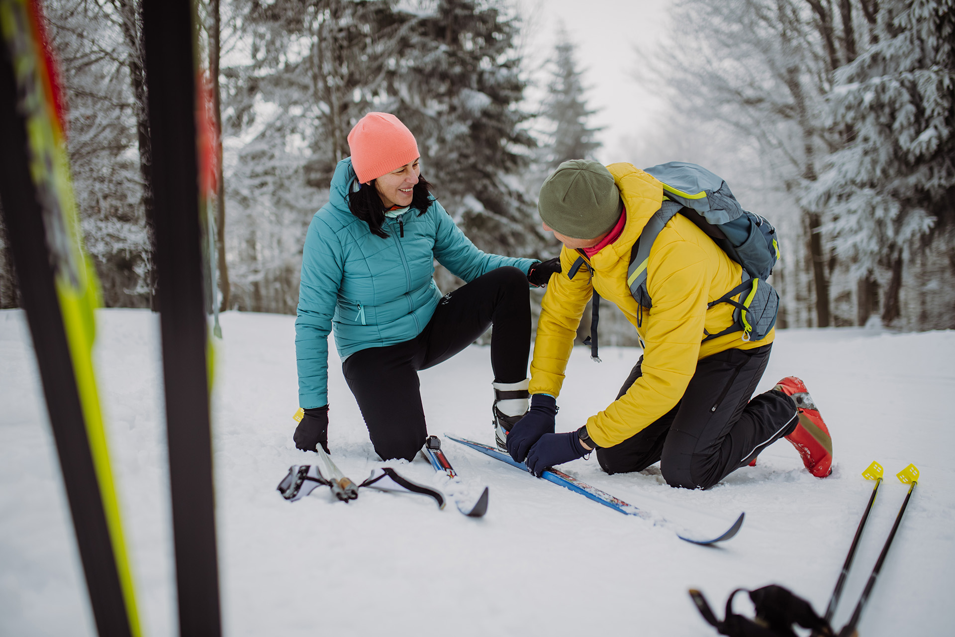 Mann hjelper dame med å få på seg ski